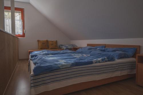 a bedroom with a bed with blue sheets and a window at Olajos Apartman in Berekfürdő