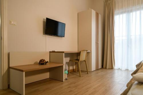 a hotel room with a desk and a tv on the wall at Bee Happy - Bed and Breakfast in Zafferana Etnea