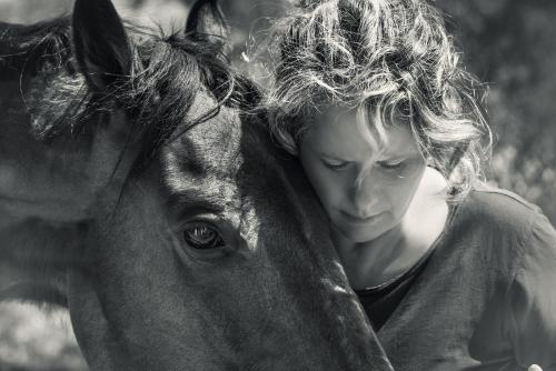 a young girl is hugging the side of a horse at The Olive Yard in Gythio