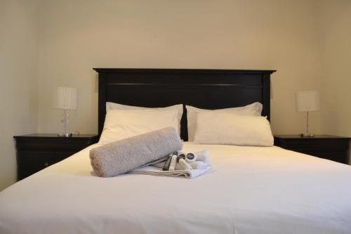 a bed with a towel and a pair of shoes on it at Hush Guest House in Northam