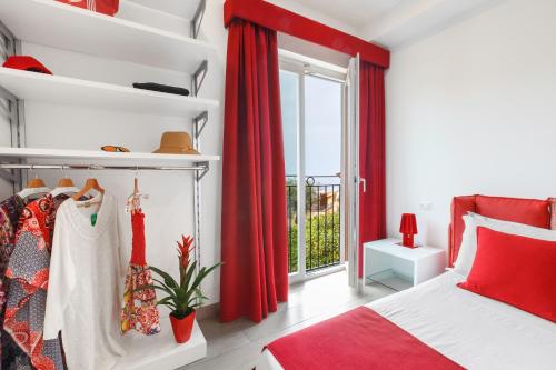 1 dormitorio con cortinas rojas, 1 cama y ventana en Eterea Charming Suites, en Sorrento