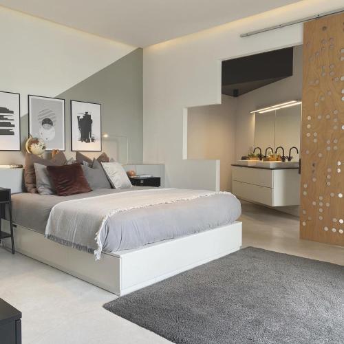 a white bedroom with a large bed and a bathroom at EBLI Corner in San Miguel de Salinas