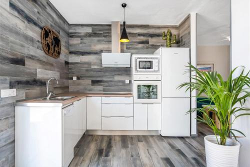 a kitchen with white appliances and a wooden wall at Casa Mirajanda in Vejer de la Frontera