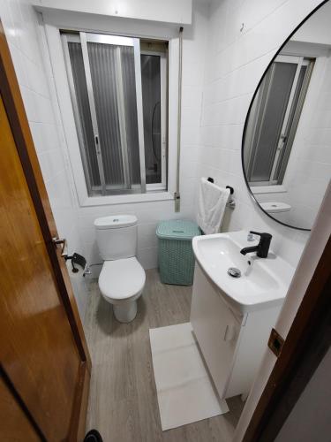 uma casa de banho com um WC, um lavatório e um espelho. em TRAVIESAS, MANOLO MARTINEZ. em Vigo