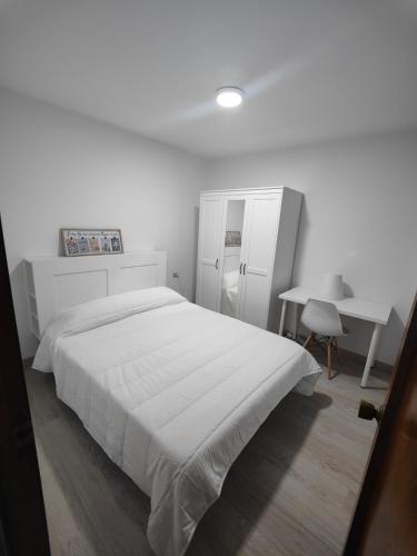 a white bedroom with a large bed and a desk at TRAVIESAS, MANOLO MARTINEZ. in Vigo