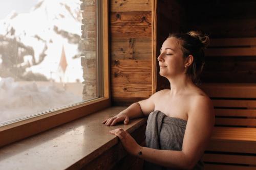 a woman is looking out of a window at AlpenParks Hotel & Apartment Arlberg Warth mit Pool in Warth am Arlberg