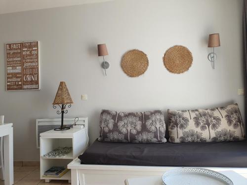 - un salon avec un canapé et un mur blanc dans l'établissement Appartement vue mer en residence piscines, à Les Sables-dʼOlonne