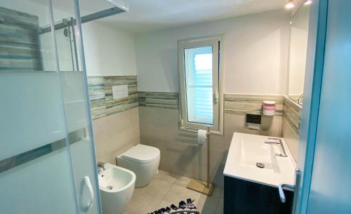 a bathroom with a sink and a toilet and a window at Santu Juanne -Ammentos Posada- a due passi dalla spiaggia in San Giovanni