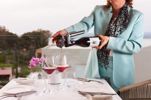 a woman pouring a glass of wine at a table at Sun and Sea Plus Resort in Plaka