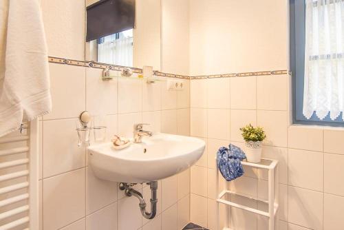 ein weißes Waschbecken in einem weiß gefliesten Bad in der Unterkunft Ferienwohnungen in der Ferienanlage Kap Arkona in Putgarten