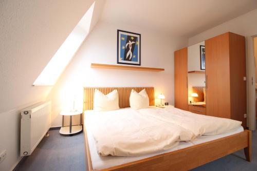 Schlafzimmer mit einem großen weißen Bett und einem Dachfenster in der Unterkunft Hafenhäuser Breege - Ferienwohnung 9 Strandläufer in Breege