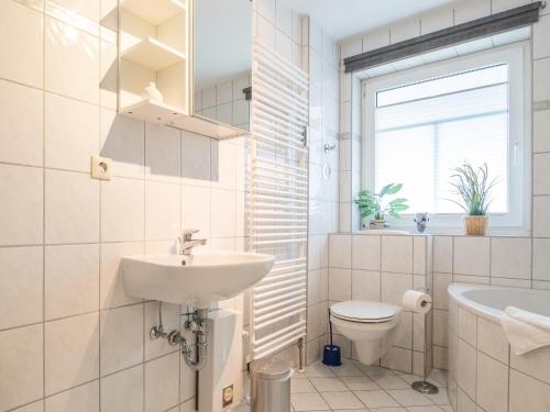 a white bathroom with a sink and a toilet at Ferienwohnung Naurulokki in Baabe