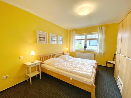 um quarto amarelo com uma cama e uma janela em Ferienhaus Sabrina em Sassnitz