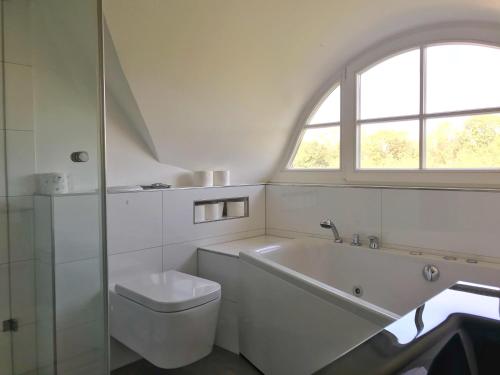 グロヴェにあるFerienhaus Sarcanderのバスルーム(バスタブ、トイレ付)、窓が備わります。