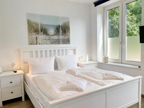 a white bedroom with a white bed and a window at Gross Stresow Ferienwohnung Vilm E in Groß Stresow