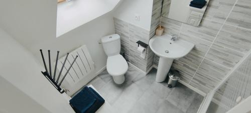 une salle de bain blanche avec des toilettes et un lavabo dans l'établissement Chaleureuse petite maison de bourg, à Beaumont-sur-Sarthe
