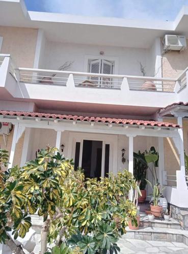 a white house with a tree in front of it at Gioula's Residence in Patitiri