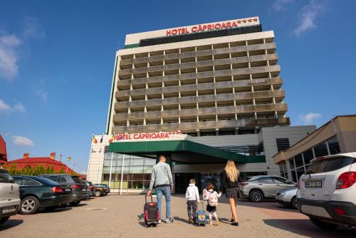 un hombre y dos niños caminando frente a un hotel en Caprioara Spa&Wellness Resort en Covasna