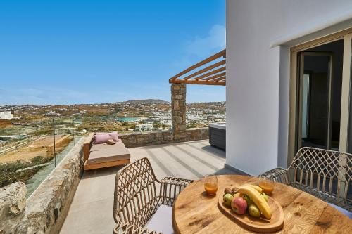 einen Holztisch mit einem Obstteller auf dem Balkon in der Unterkunft Due Mari Mykonos in Agios Ioannis Mykonos