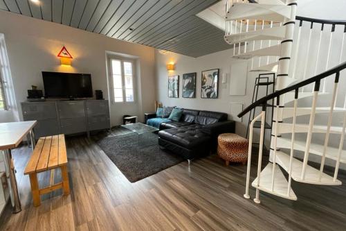 - un salon avec un canapé en cuir noir et un escalier en colimaçon dans l'établissement Riouffe 2 bedroom duplex apartment in the center of Cannes, à Cannes