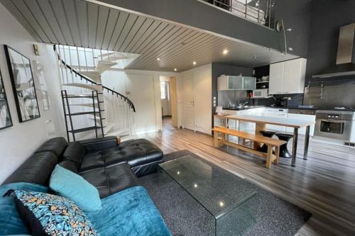 un salon avec un canapé noir et une cuisine dans l'établissement Riouffe 2 bedroom duplex apartment in the center of Cannes, à Cannes