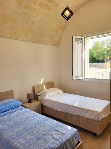 two beds in a room with a window at Appartamento Le Sorgenti in Torre Vado