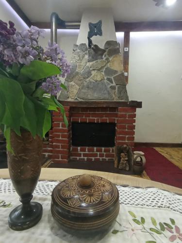 a vase of lilacs sitting on a table with a fireplace at Konaciste Mali Izvor in Boljevac