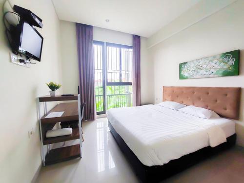 a bedroom with a bed and a tv and a window at Olivia SOHO Guest House in Legian