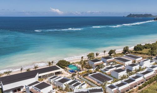 an aerial view of a beach with houses and the ocean at Amber Lombok Beach Resort in Selong Belanak