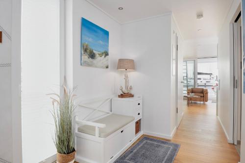 a white hallway with a desk and a plant at Hausboot Ankerplatz - Floating Home 2 in Laboe