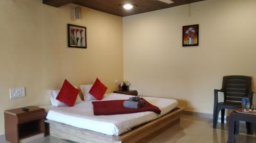Un dormitorio con una cama con almohadas rojas y una silla en Bluebell Residency, en Mahabaleshwar