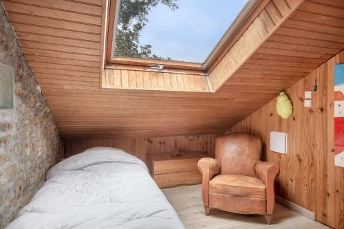 a bedroom with a bed and a chair and a window at Golfe du Morbihan, Maison de charme pour 6 in Sarzeau