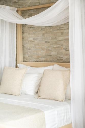 a bed with white sheets and pillows at Cyano Hotel in Plakias