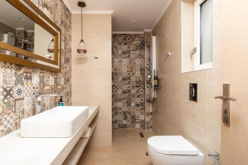a bathroom with a sink and a toilet and a shower at Cyano Hotel in Plakias