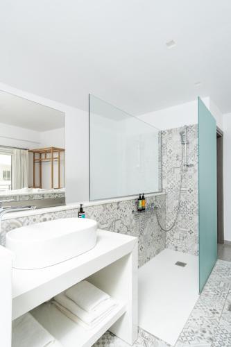 a white bathroom with a sink and a shower at Cyano Hotel in Plakias
