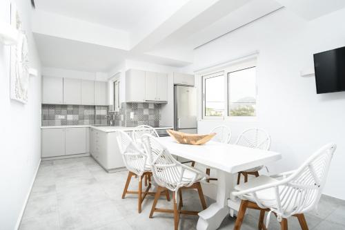 a white kitchen with a white table and chairs at Cyano Hotel in Plakias
