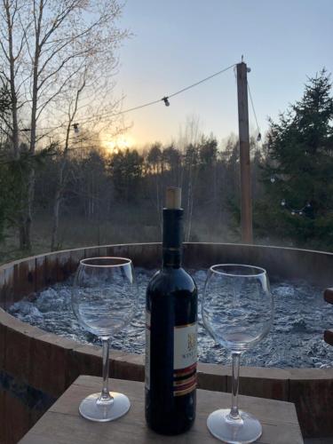 a bottle of wine and two wine glasses on a table at Koziula - Domki i Leśne SPA na Kaszubach in Przywidz