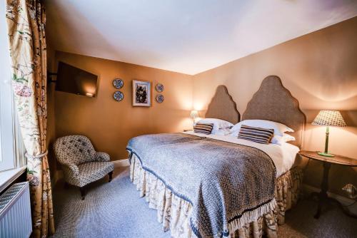 a bedroom with a large bed and a chair at High Force Hotel in Newbiggin