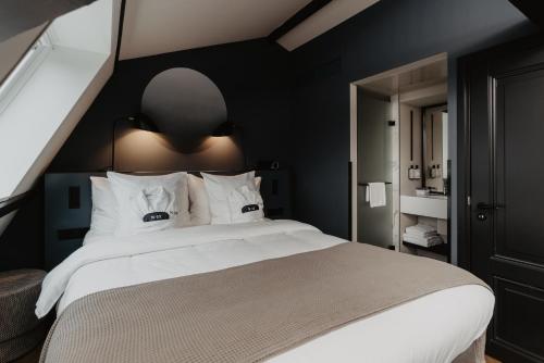 a bedroom with a large white bed with black walls at The Nox Hotel in Utrecht
