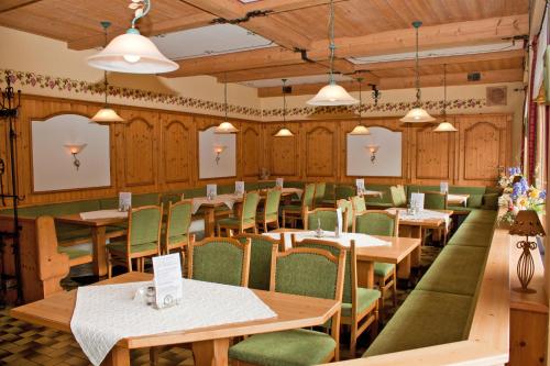 a dining room with wooden tables and green chairs at Hotel Binderhäusl in Berchtesgaden