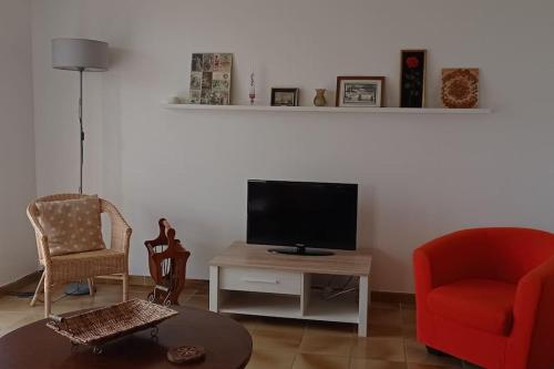 博凱爾的住宿－UNE CHOUETTE MAISON，客厅配有电视、2把椅子和1张桌子