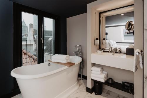 a bathroom with a tub and a sink and a mirror at The Nox Hotel in Utrecht