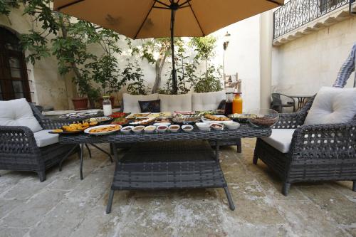a table with food on it with chairs and an umbrella at Kaliruha Boutique Hotel in Sanlıurfa