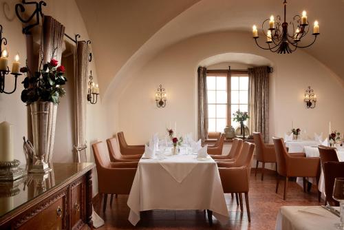 a restaurant with white tables and chairs and a chandelier at Hotel Schloss Mittersill in Mittersill