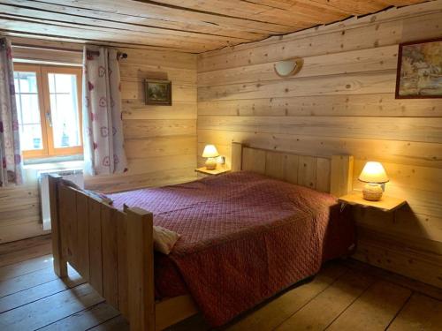 une chambre avec un lit dans une cabane en rondins dans l'établissement La ferme du Savetier, à Sangot