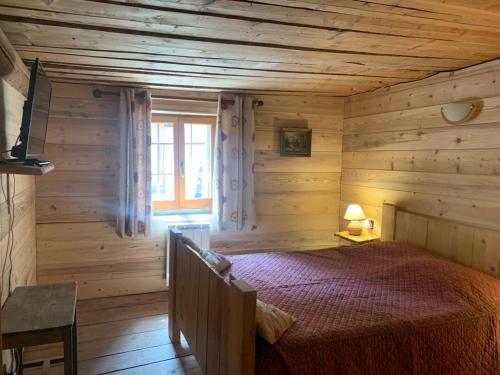 une chambre avec un lit dans une cabane en rondins dans l'établissement La ferme du Savetier, à Sangot