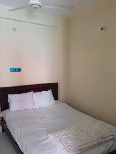 1 cama con sábanas blancas y almohadas en una habitación en Hotel GM Palace en Chittagong