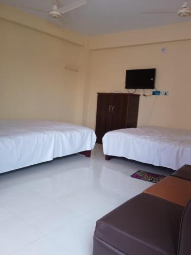Habitación con 2 camas y TV en la pared. en Hotel GM Palace en Chittagong