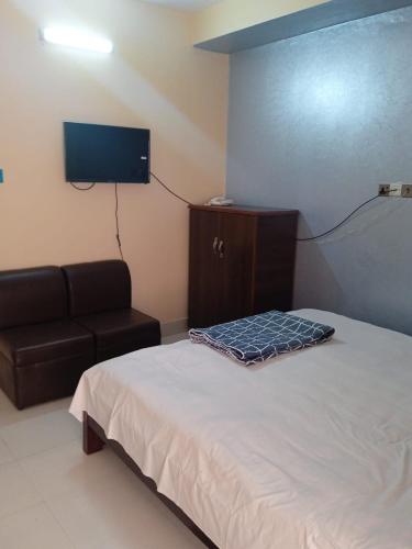 1 dormitorio con cama, sofá y TV de pantalla plana en Hotel GM Palace en Chittagong