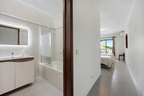 a white bathroom with a tub and a sink and a bath tub at Apartamento Mar-colina-sol in Carvoeiro